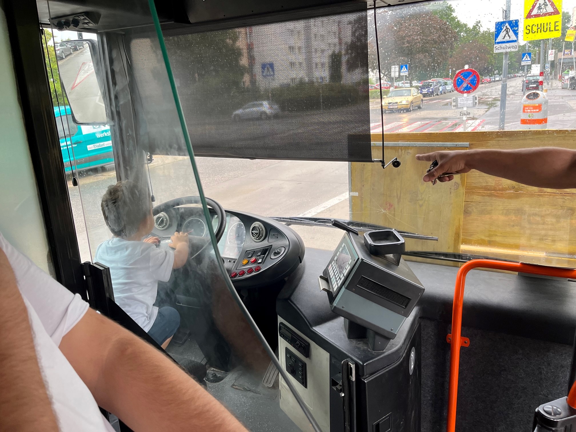 Ein kleines Kind sitzt hinter dem Steuer des Bus-Labors, einem umgebauten ehemaligen Wiener-Linien Bus. Konzentriert starrt es in die Ferne, die Hände am Lenkrad. Fährt es oder steht es?